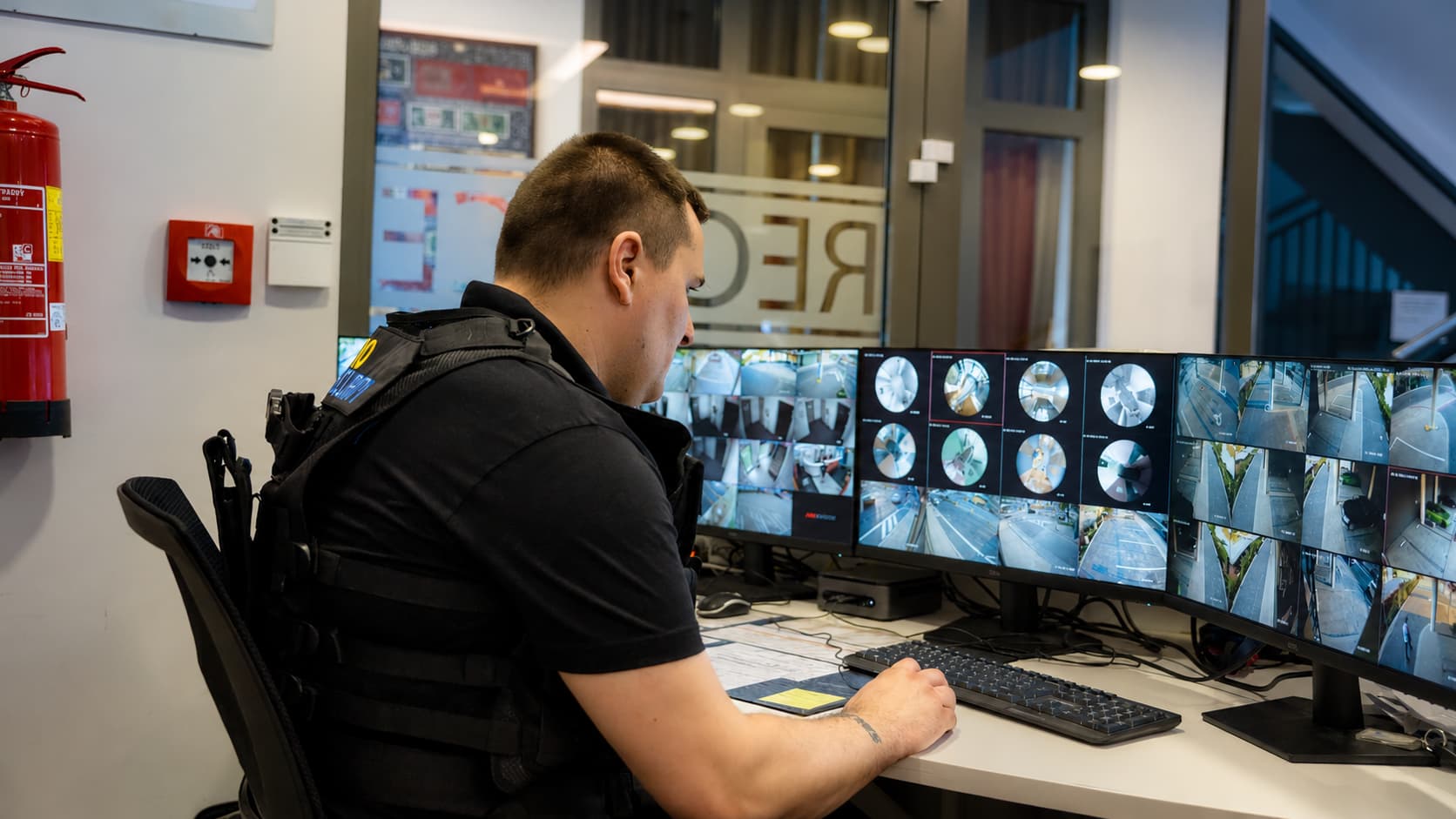 Bezpečnostní pracovník kontroluje kamerový systém při ochraně firemního objektu